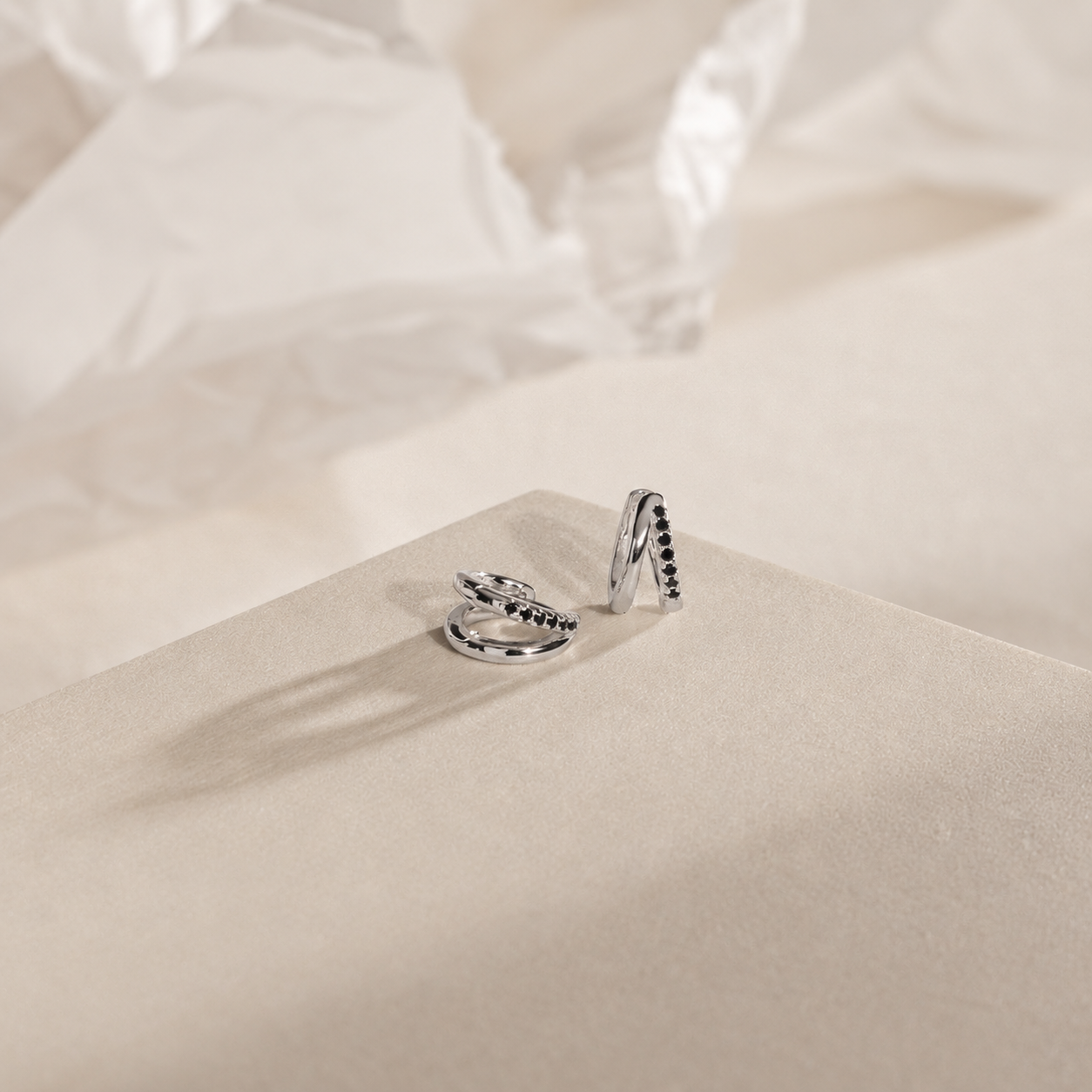 Two silver rings with black gemstones on a beige fabric background